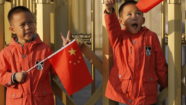 Twin boys Sun Qiyu and Sun Qichun hold China's national flags on the Tiananmen Gate in Beijing Nov. 2, 2015. 