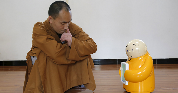 Master Xianfan looks at robot monk Xian'er as he demonstrates the robot's conversation function during a photo opportunity in Longquan Buddhist temple on the outskirts of Beijing, April 20, 2016.