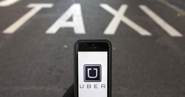 The logo of car-sharing service app Uber on a smartphone over a reserved lane for taxis in a street is seen in this photo illustration taken in Madrid on December 10, 2014.