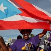 A member of a labor union shouts slogans while holding a Puerto Rico flag during a protest in San Juan Sept. 11, 2015.