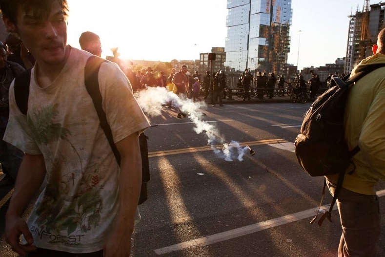 A police flashbang device lands just before exploding among a crowd of protesters.