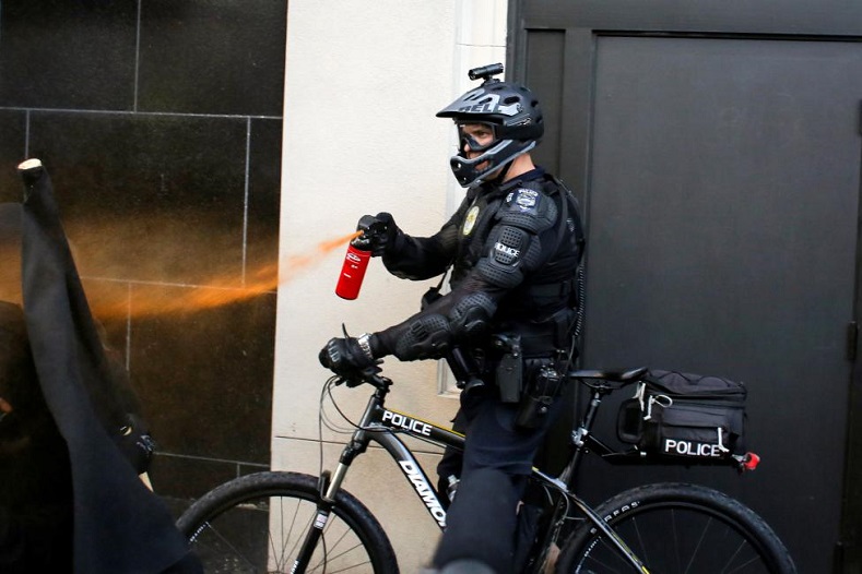 A police officer uses pepper spray .