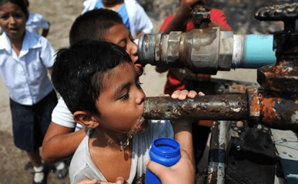 Salvadoran children drink water from a pipe, March 20, 2013. 