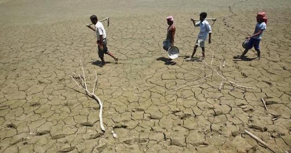 Laborers walk through a parched land of a dried lake on the outskirts of Agartala, capital of India's northeastern state of Tripura.