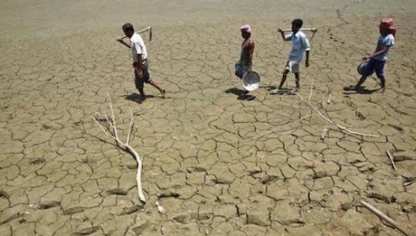 Laborers walk through a parched land of a dried lake on the outskirts of Agartala, capital of India's northeastern state of Tripura. 