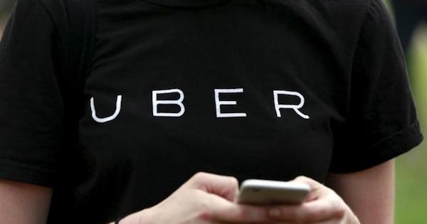 An Uber representative registers people on his smartphone during the kick off of a citywide jobs tour in the Queens borough of New York