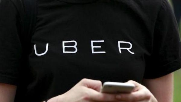 An Uber representative registers people on his smartphone during the kick off of a citywide jobs tour in the Queens borough of New York 