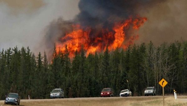 A wildfire burns as evacuees who were stranded north of Fort McMurray, Alberta, Canada head south of Fort McMurray on Highway 63.