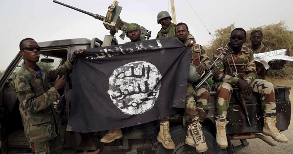 Nigerian soldiers hold up a Boko Haram flag that they had seized in the recently retaken town of Damasak, Nigeria.