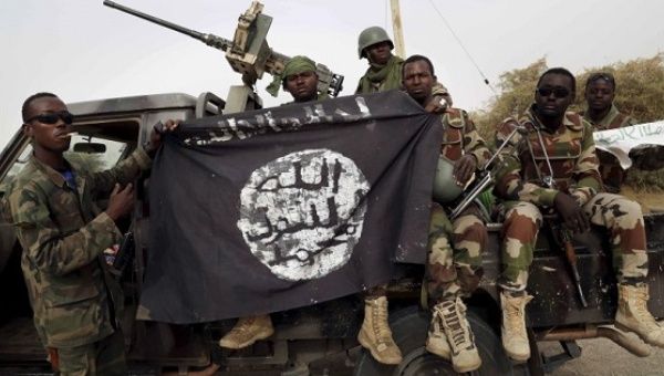 Nigerian soldiers hold up a Boko Haram flag that they had seized in the recently retaken town of Damasak, Nigeria.