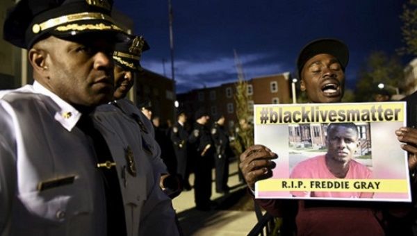 A demonstrator holds a sign in front of the Baltimore Police Department Western District station during a protest against the death in police custody of Freddie Gray in Baltimore April 23, 2015.