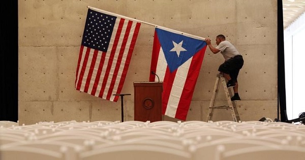 A worker takes off U.S and Puerto Rican flag after rally of U.S. Democratic presidential candidate Bernie Sanders in San Juan, Puerto Rico.