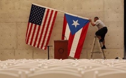 A worker takes off U.S and Puerto Rican flag after rally of U.S. Democratic presidential candidate Bernie Sanders in San Juan, Puerto Rico.