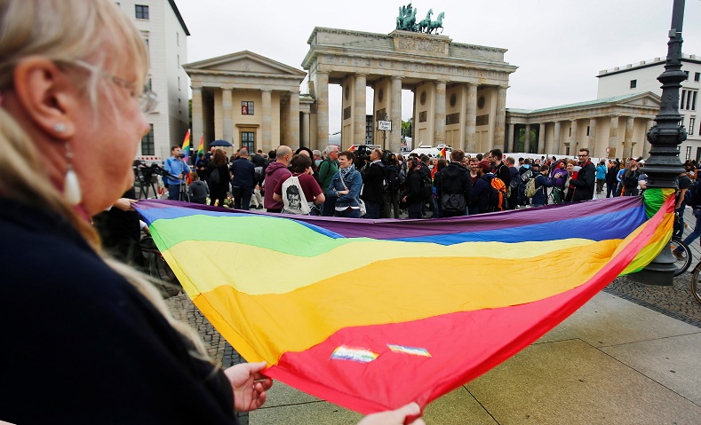 People display a huge rainbow flag for the victims of the shooting at a gay nightclub in Orlando in front of the U.S. Embassy in Berlin, Germany, June 13, 2016.