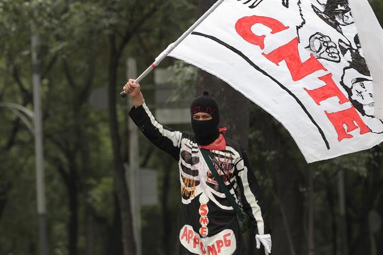 A demonstrator waves a flag with teachers of the CNTE from Guerrero, Chiapas, Oaxaca and Michoacan who marched towards the official residence of Los Pinos on June 11, 2016.