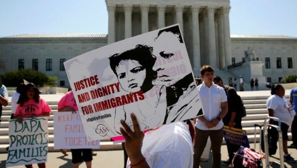 Demonstrators from the immigrant community advocacy group CASA carry signs at the Supreme Court building in Washington, U.S. June 20, 2016.