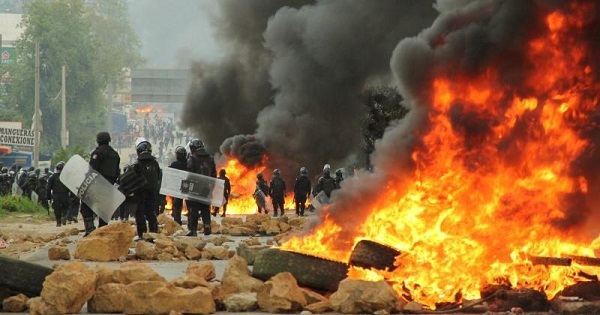 Riot police officers stand guard next to a burning barricade after clashes during a protest of neoliberal education reforms, Nochixtlan, Oaxaca, June 19, 2016.