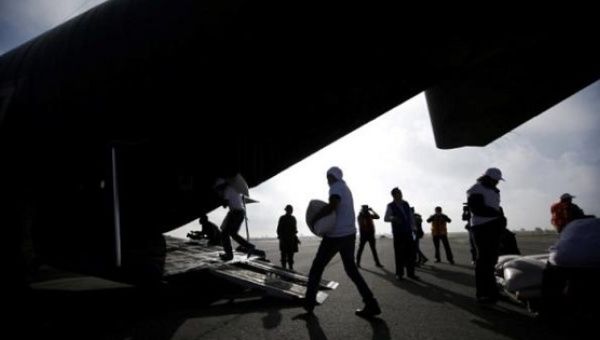 Workers unload sacks filled with grain from a C-130 Hercules aircraft to be distributed in impoverished communities of Oaxaca state.