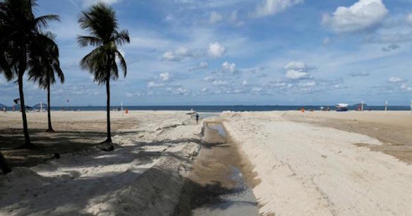 A man runs next to sewage system flowing on Copacabana beach in Rio de Janeiro, Brazil, June 9, 2016.