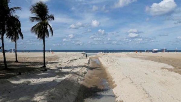 A man runs next to sewage system flowing on Copacabana beach in Rio de Janeiro, Brazil, June 9, 2016.