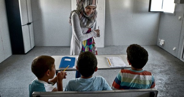 A teacher gives English lessons to children in a container converted into a classroom on June 24, 2016 at the refugee camp of Skaramangs, south of Athens.