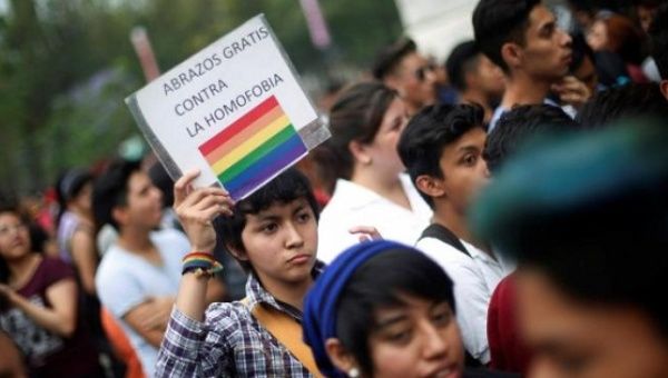 A member of the LGBT community holds a sign that reads 'Free hugs against homophobia' during a Kissathon to celebrate International Day Against Homophobia, outside Bellas Artes museum in Mexico City, Mexico, May 17, 2016.