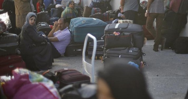 Palestinians sit next to their suitcases as they wait to cross into Egypt, at the Rafah crossing between Egypt and the Gaza Strip, June 13, 2015.