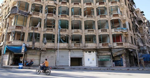A man rides a motorcycle past a damaged building in the rebel-held al-Shaar neighbourhood of Aleppo, Syria, September 17, 2016.