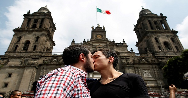 A couple kiss each other in front of the cathedral during a march in support of gay marriage, sexual and gender diversity in Mexico City on September 11, 2016.