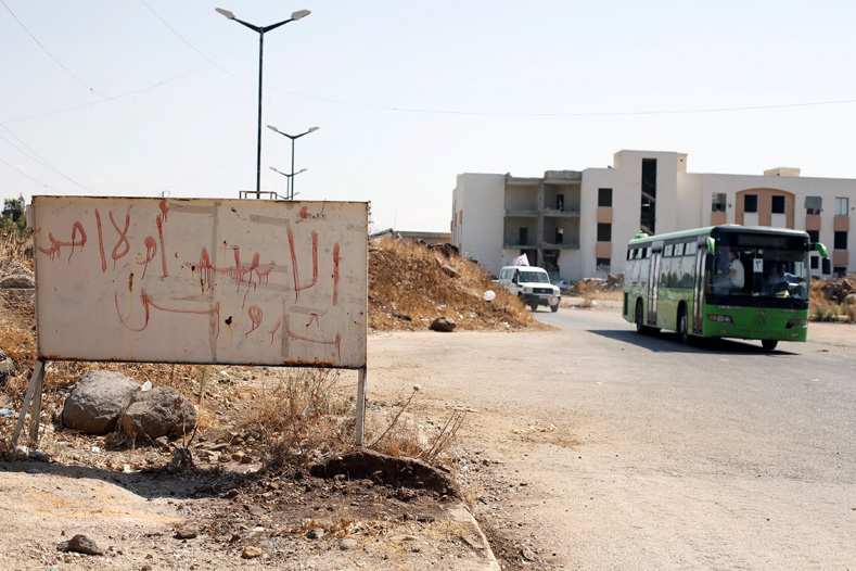 A bus with Syrian rebels and their families evacuating the besieged Waer district in the central Syrian city of Homs is pictured after a local agreement reached between rebels and Syria's army, Syria, Sept. 22, 2016. The graffiti on the sign reads in Arabic: