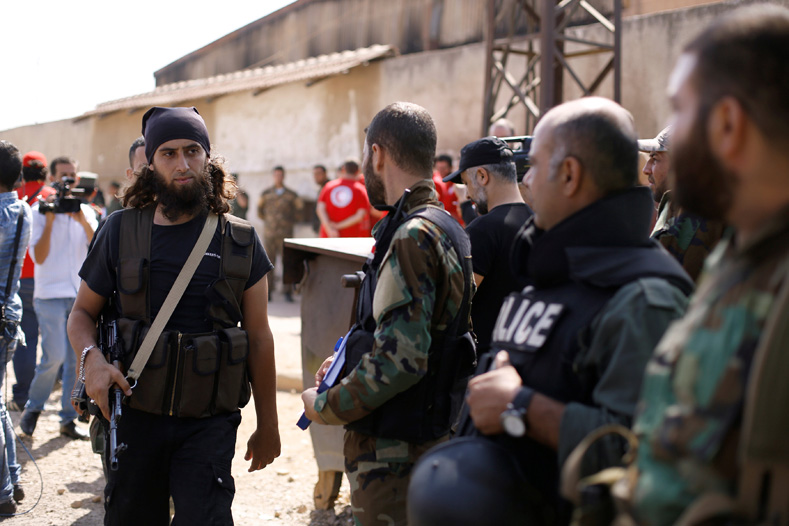 A rebel fighter (L) walks next to Syrian Army soldiers prior to evacuating the besieged Waer district in the central Syrian city of Homs, after a local agreement reached between rebels and Syria's army, Syria Sept. 22, 2016.