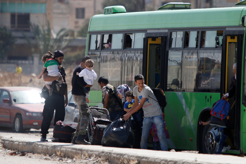 Syrian rebels and their families carry their luggage into a bus to evacuate the besieged Waer district in the central Syrian city of Homs, after a local agreement reached between rebels and Syria's army, Syria Sept. 22, 2016.