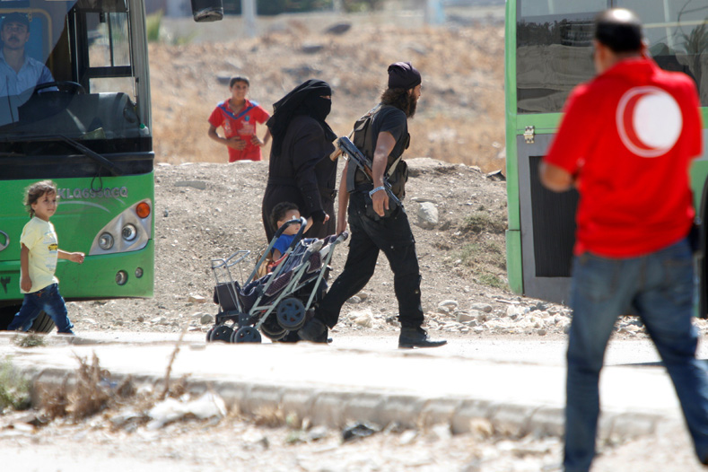 A Syrian rebel and his family walk towards a bus to evacuate the besieged Waer district in the central Syrian city of Homs, after a local agreement reached between rebels and Syria's army, Syria Sept. 22, 2016.