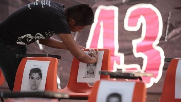 A student in Tixtla, Mexico, places a photograph at a memorial dedicated to the 43 missing Ayotzinapa students.