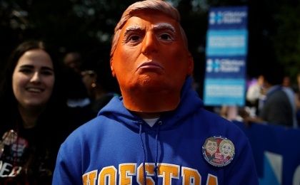 A man stands while wearing a mask depicting Republican nominee Donald Trump outside Hofstra University, Sept. 26, 2016.