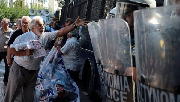 A Greek pensioner shouts at riot police following scuffles during a demonstration against planned pension cuts, Athens, Greece, Oct. 3, 2016.