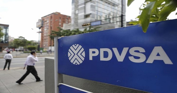 People walk past a sign with a PDVSA logo at its gas station in Caracas, October 28, 2015.
