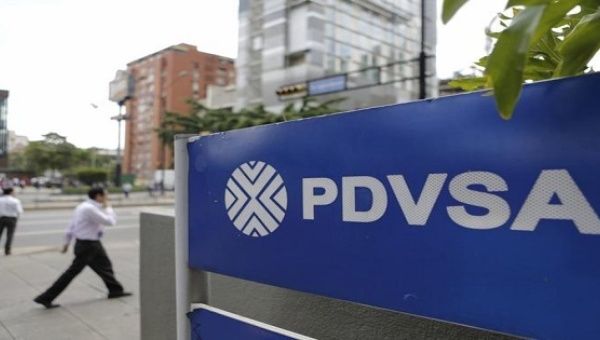 People walk past a sign with a PDVSA logo at its gas station in Caracas, October 28, 2015.