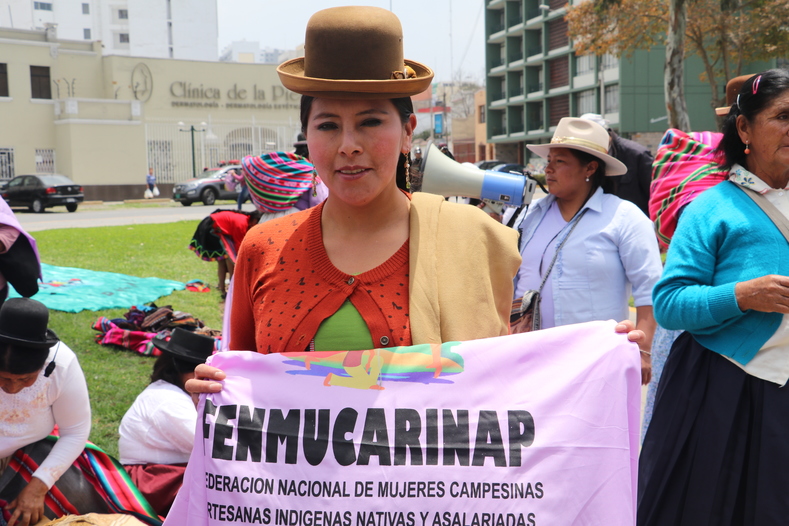 Rita Choquehuanca, wearing a traditional hat of Puno, displays the flag of the National Federation of Campesinas.