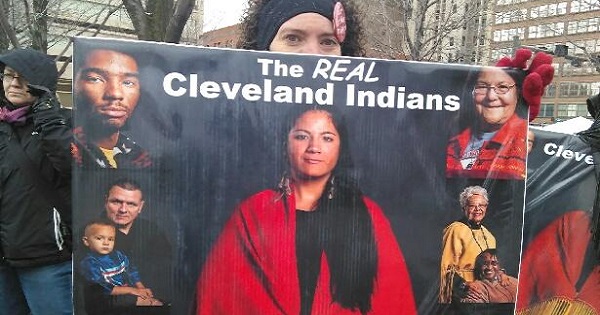 An unidentified protester holds a sign in protest of the Cleveland Indians's name.