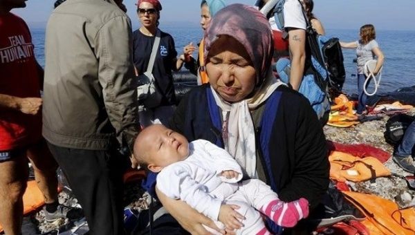 An Afghan refugee holds her three-month-old baby girl Zainab after arriving at a beach on the Greek island of Lesbos after crossing a part of the Aegean sea from Turkey Sept. 17, 2015. 