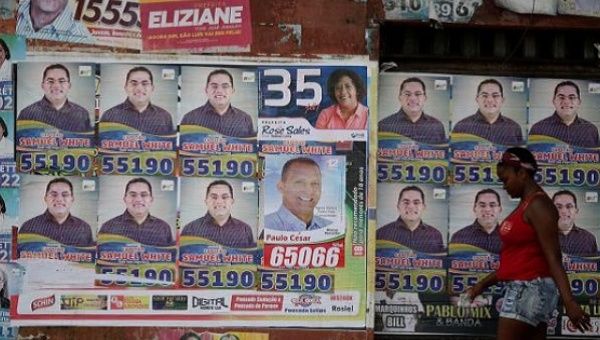 A woman walks past election posters during the first round of municipal elections in Sao Luis, Brazil.