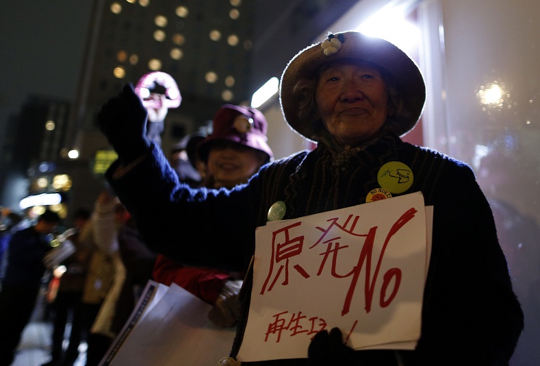 A protester holding a banner rises her fist during an anti-nuclear rally in front of the headquarters of Tokyo Electric Power Co (TEPCO), the operator of the tsunami-crippledFukushima Daiichi nuclear plant, a day before the five-year anniversary of the disaster, in Tokyo, Japan, March 10, 2016. The banner reads in Japanese 