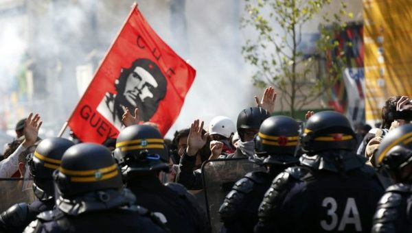 Youths raise their hands high to show that they do not hold bottles or stones as they pass French riot police during the May Day march in Paris, France, May 1, 2016.