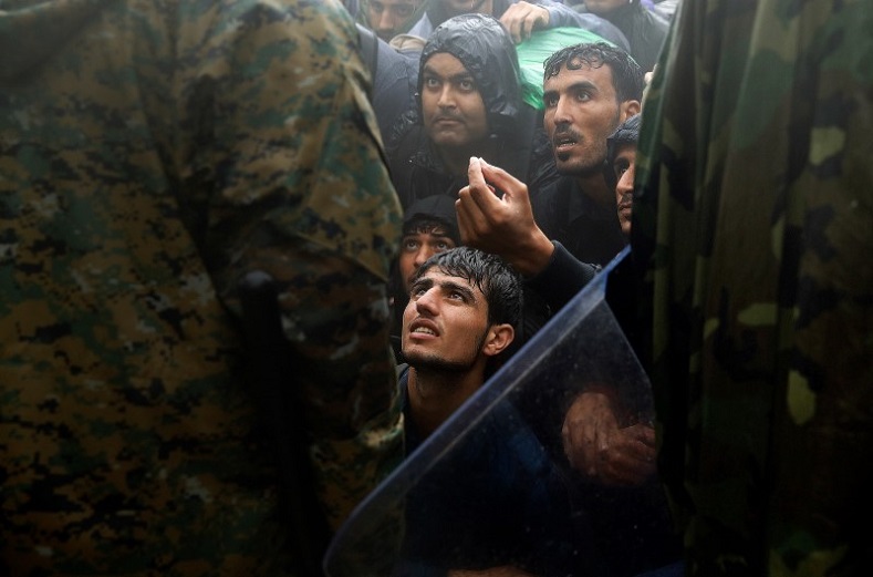 Migrants and refugees beg Macedonian policemen to allow passage to cross the border from Greece into Macedonia during a rainstorm, near the Greek village of Idomeni, September 10, 2015.
