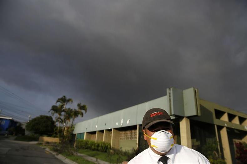 A man uses a face mask to avoid breathing ash and noxious gases.