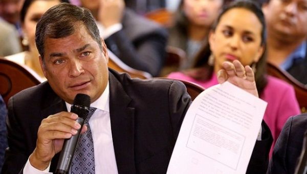 President Rafael Correa holds up a copy of the text of the tax haven plebiscite he wants the country to vote on, Quito, Ecuador, Oct. 24, 2016.