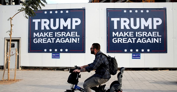 A man cycles past signs bearing the name of U.S. President-elect Donald Trump in Tel Aviv, Israel, Nov. 14, 2016.