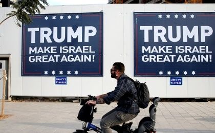 A man cycles past signs bearing the name of U.S. President-elect Donald Trump in Tel Aviv, Israel, Nov. 14, 2016.