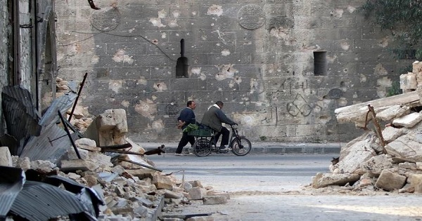 A man walks past a man riding a bicycle near the rubble of damaged buildings in the rebel held area of Old Aleppo, Syria November 14, 2016.